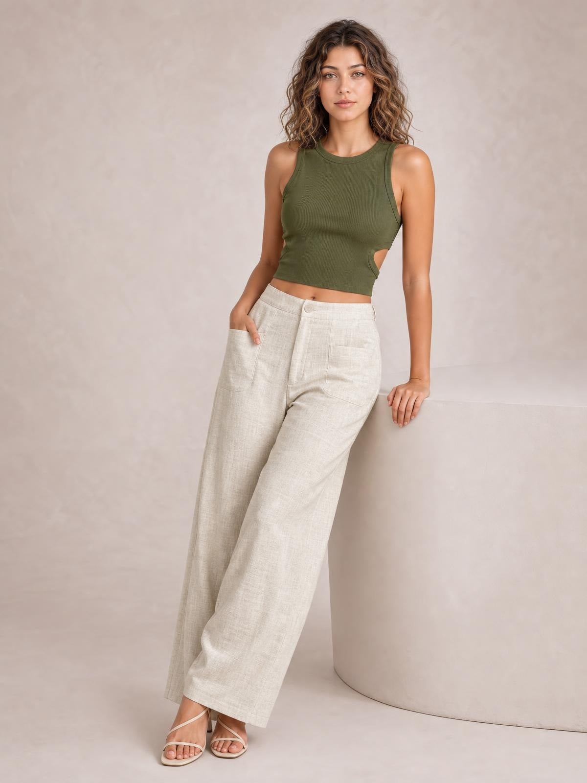 Model wearing high-waisted wide-leg pants in light beige with a buttoned zip fly, front pockets, and a relaxed full-length silhouette.