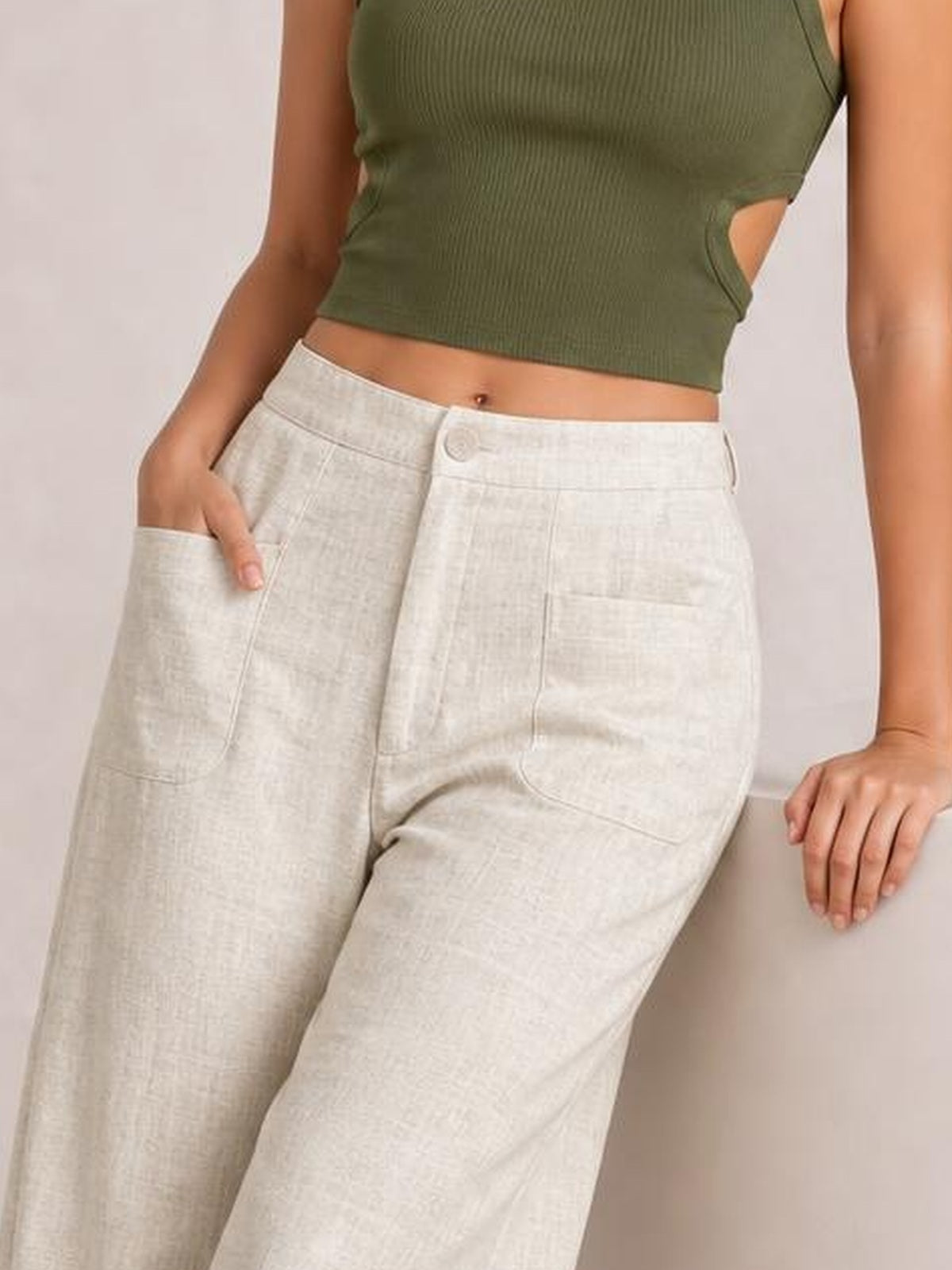 Model wearing high-waisted wide-leg pants in natural ivory with a button-and-zip fly, front pockets, and relaxed wide-leg silhouette.