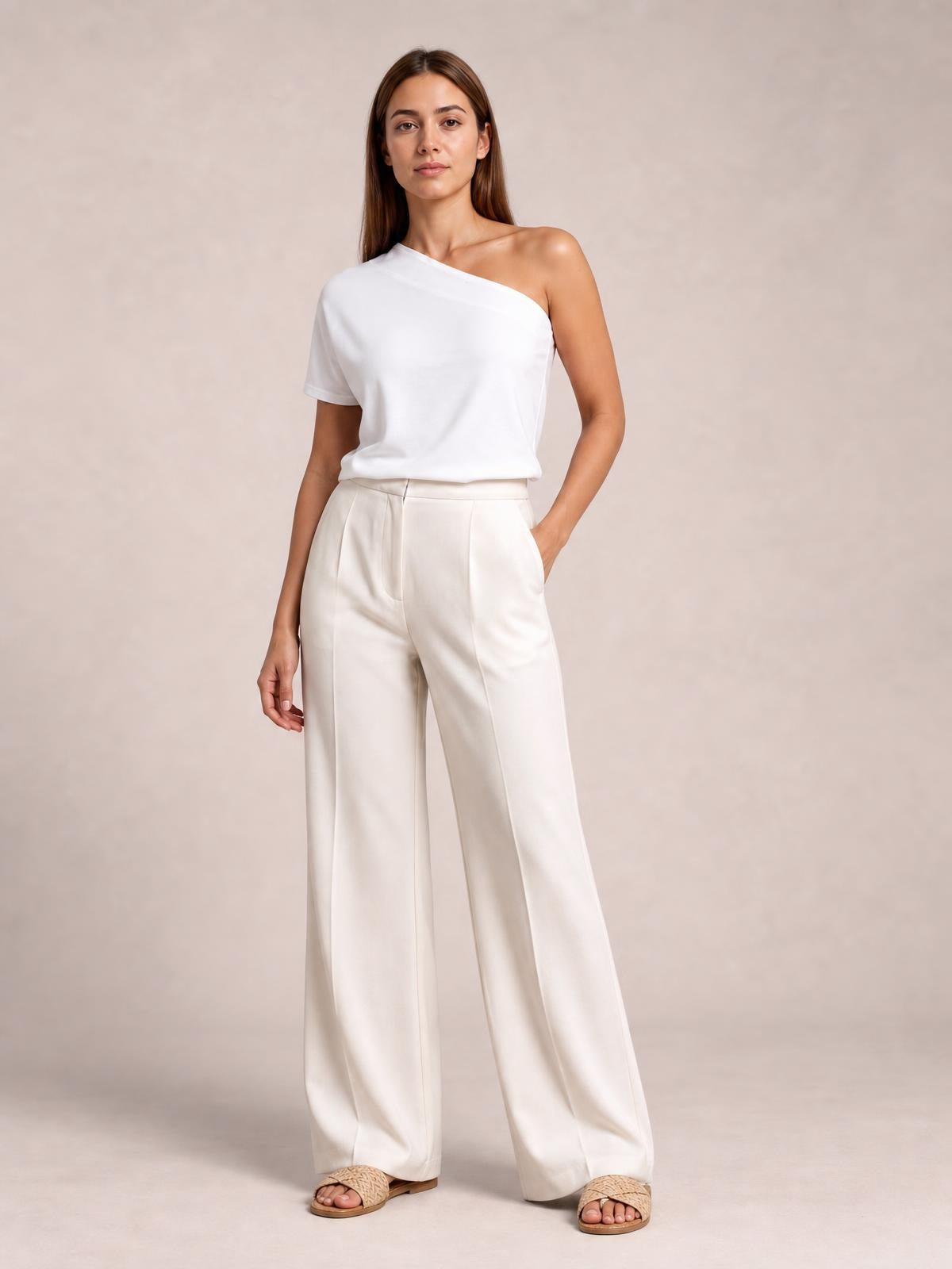 Model wearing ivory high-waisted wide-leg pants with front pleats, side pockets, a tailored waistband, and a fluid full-length silhouette.