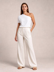 Model wearing ivory high-waisted wide-leg pants with front pleats, side pockets, a tailored waistband, and a fluid full-length silhouette.