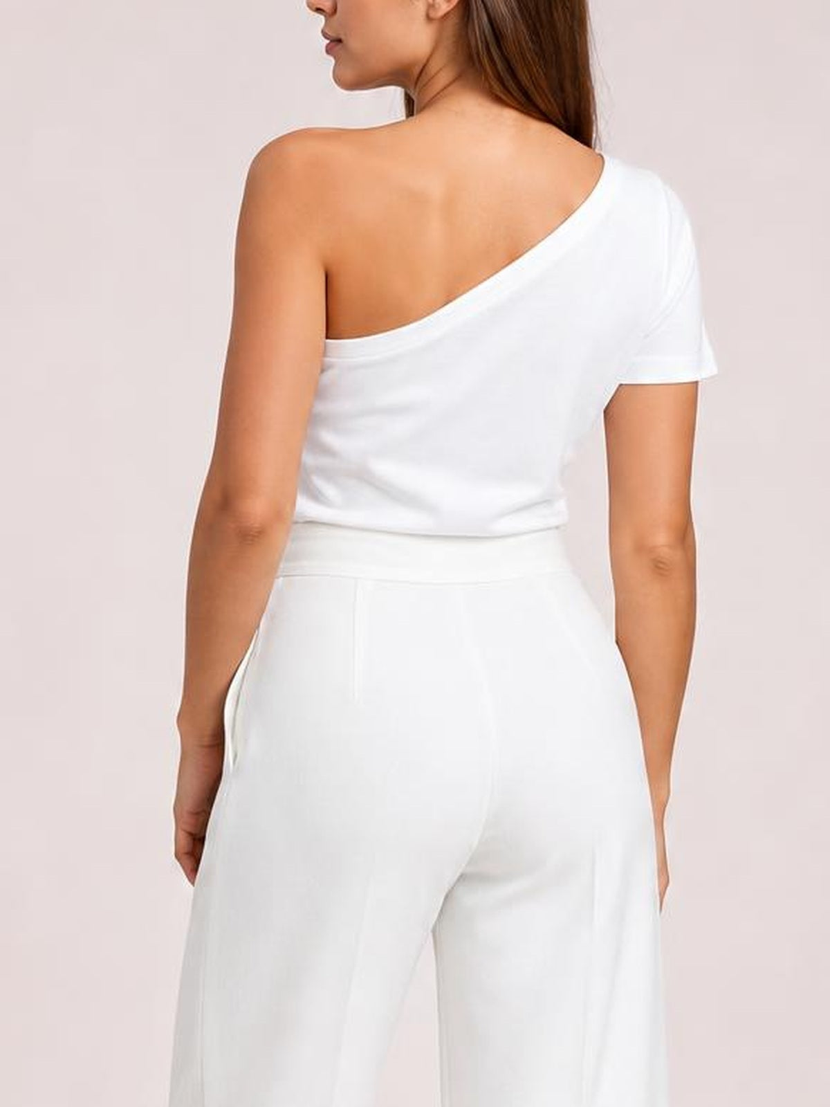 A model poses from behind in white high-waisted wide-leg pants, showing the structured waistband, relaxed silhouette, vertical seams, and side pockets.