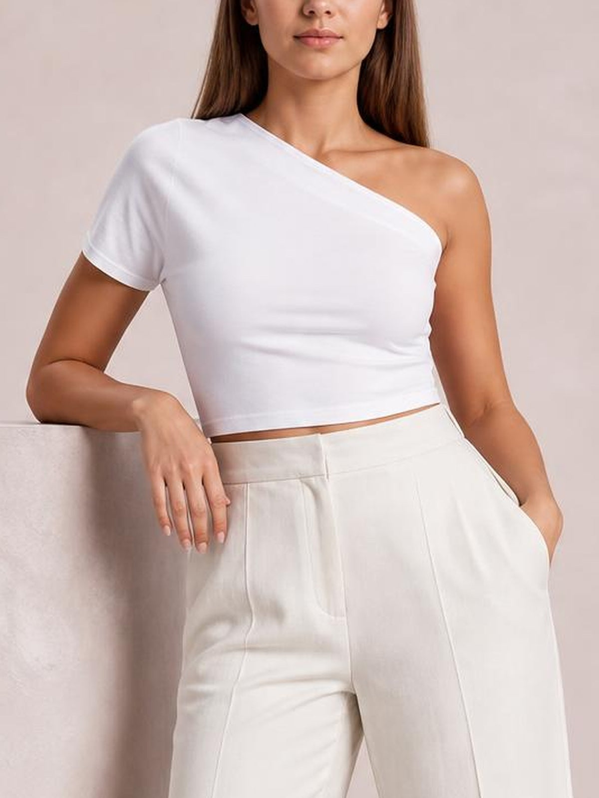 A model wears white high-waisted wide-leg pants with a structured waistband, front seam detailing, and side pockets, posing with one hand tucked into a pocket.