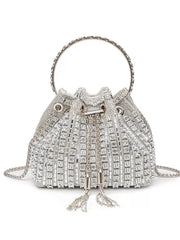 Mini silver rhinestone-embellished bucket handbag with a flared silhouette, ring handle, drawstring closure, tassel ends, and chain crossbody strap.