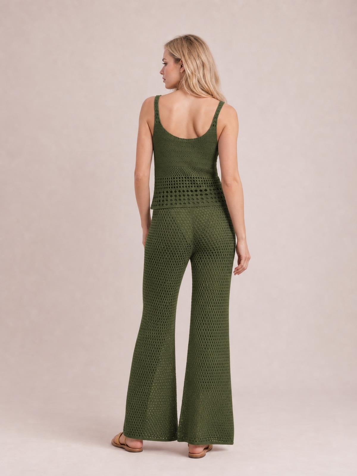 A model stands facing away in an olive-green hollow-out knit top with wide straps and coordinating wide-leg pants in an openwork sweater cover-up set.