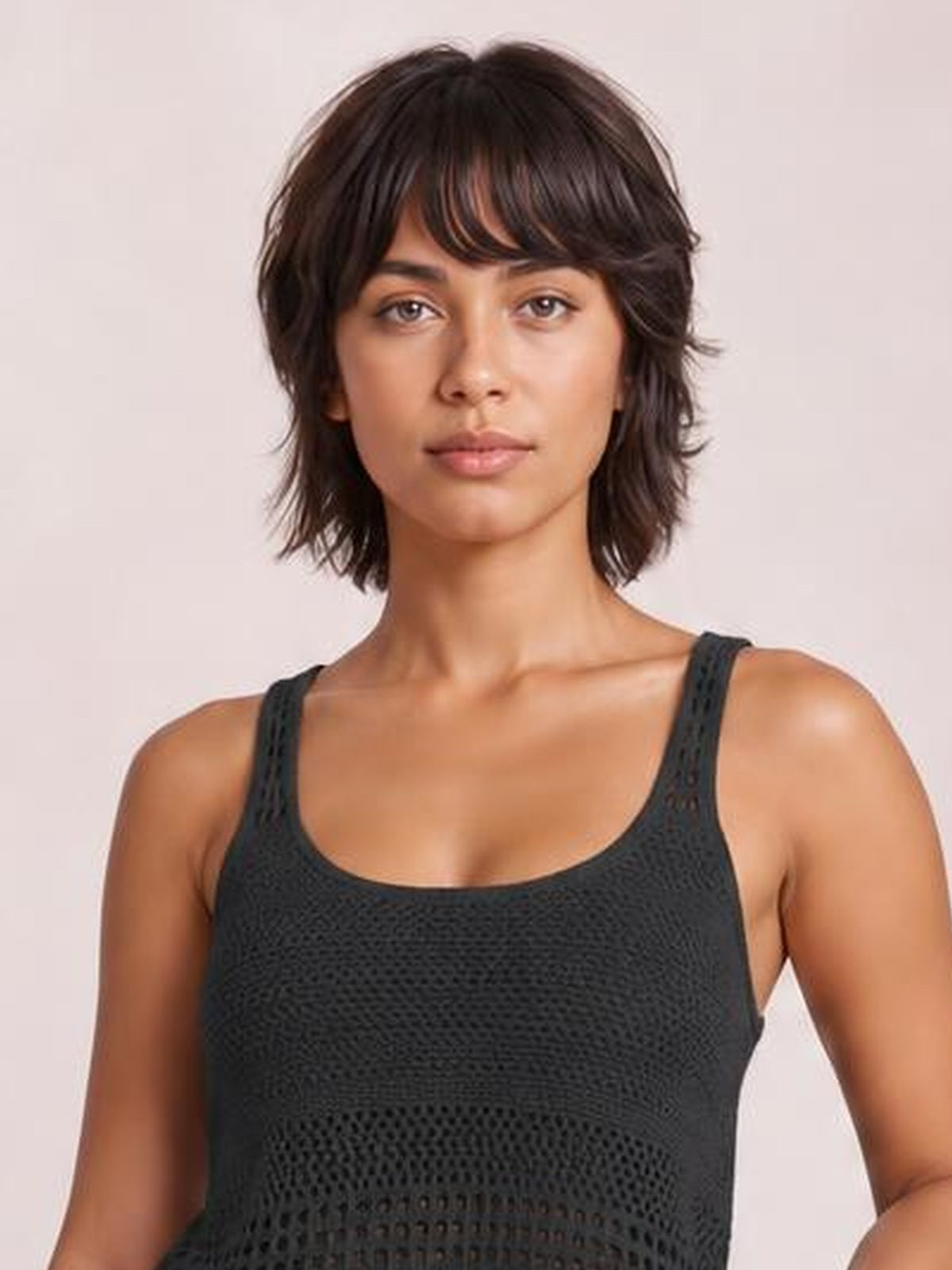 Model faces forward wearing a black sleeveless hollow-out sweater top with a rounded neckline, openwork knit construction, and a relaxed silhouette.