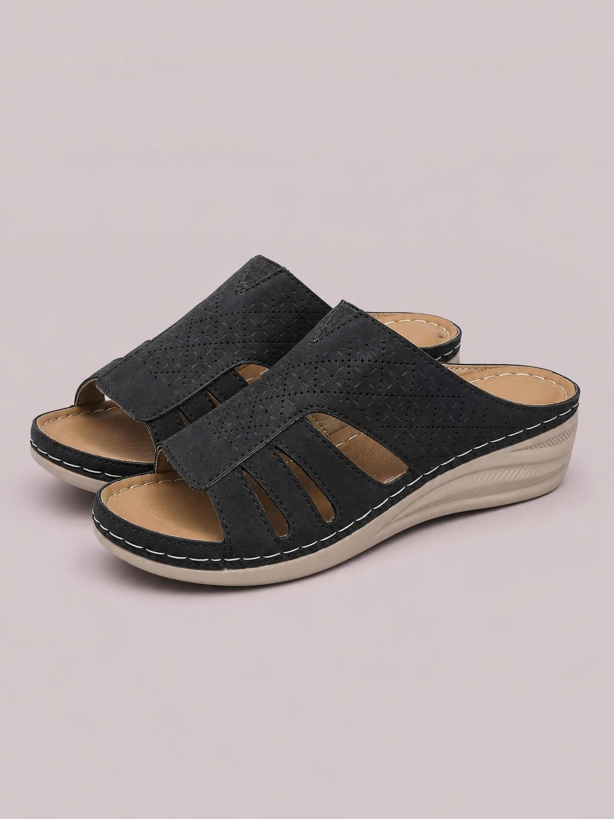 Black PU leather hollow-out wedge sandals with wide stitched straps, open toes, tan footbeds, and low beige wedge soles.