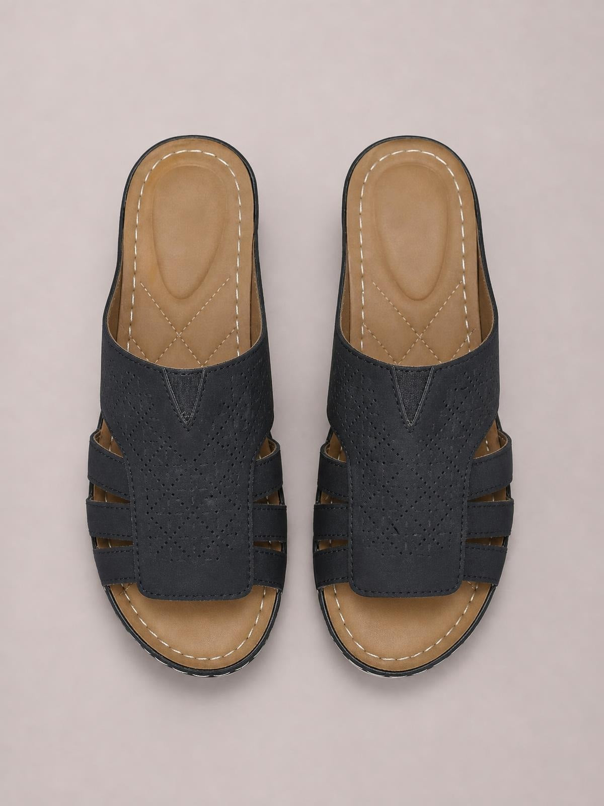 Black PU leather hollow-out wedge sandals with perforated straps, open toes, tan cushioned insoles, and stitched rubber soles.