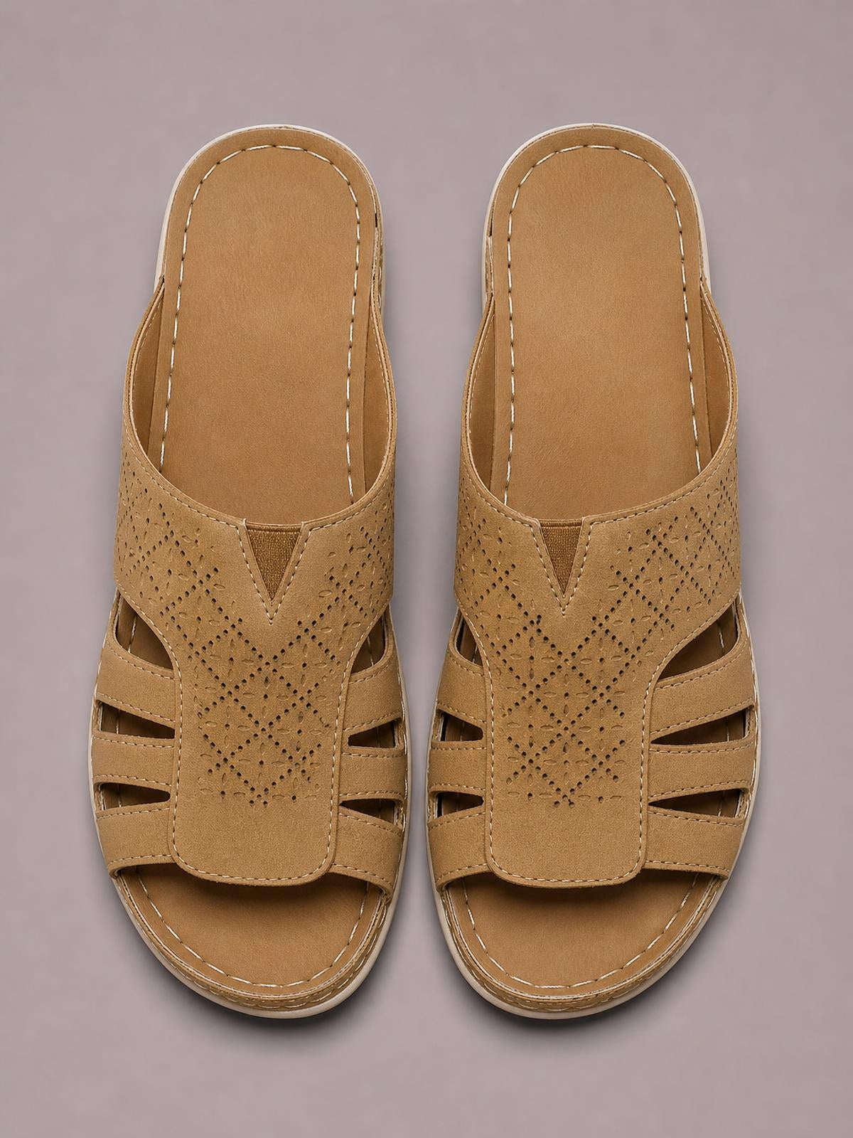 Tan hollow-out wedge sandals feature perforated PU leather uppers, open toes, layered straps, contrast stitching, and cushioned flat rubber soles.