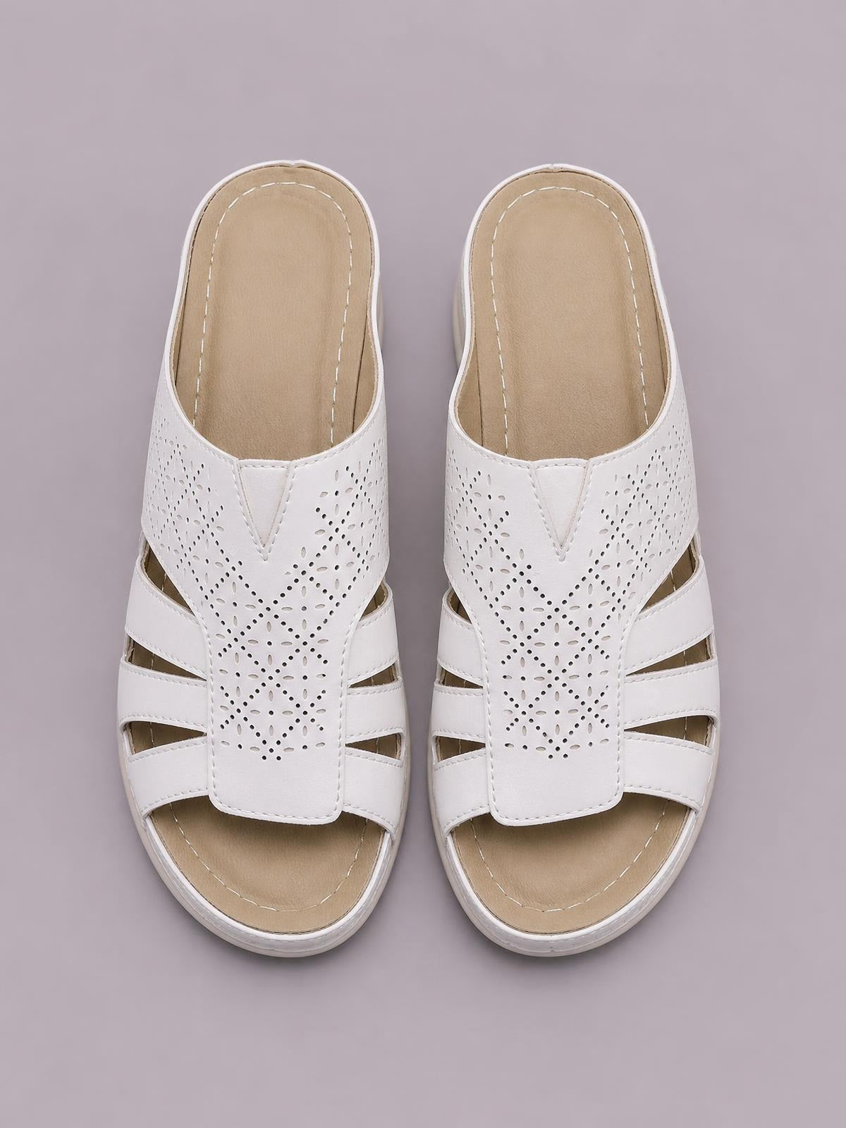 White PU leather hollow-out wedge sandals with perforated uppers, wide crossover straps, open toes, cushioned footbeds, and rubber soles.