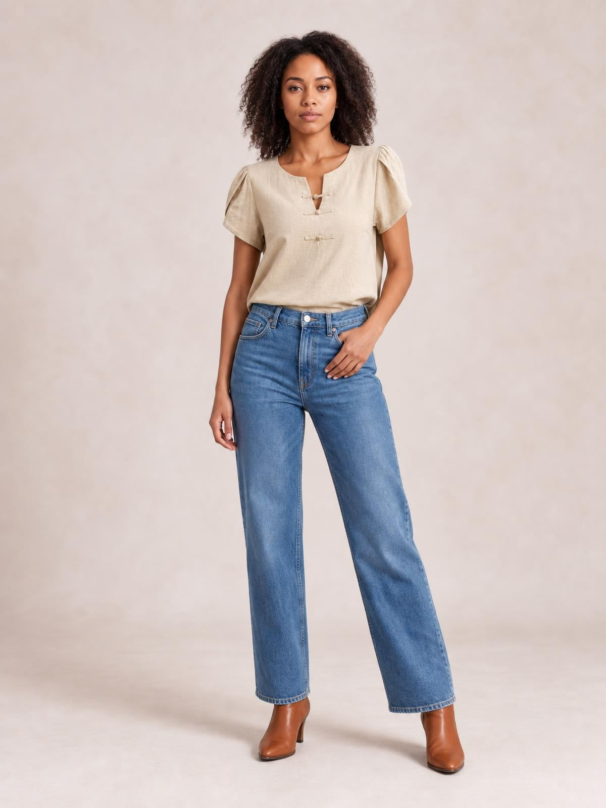 Model wears a honey notched short sleeve blouse with a relaxed silhouette, gathered shoulders, and three front closures, styled with jeans.