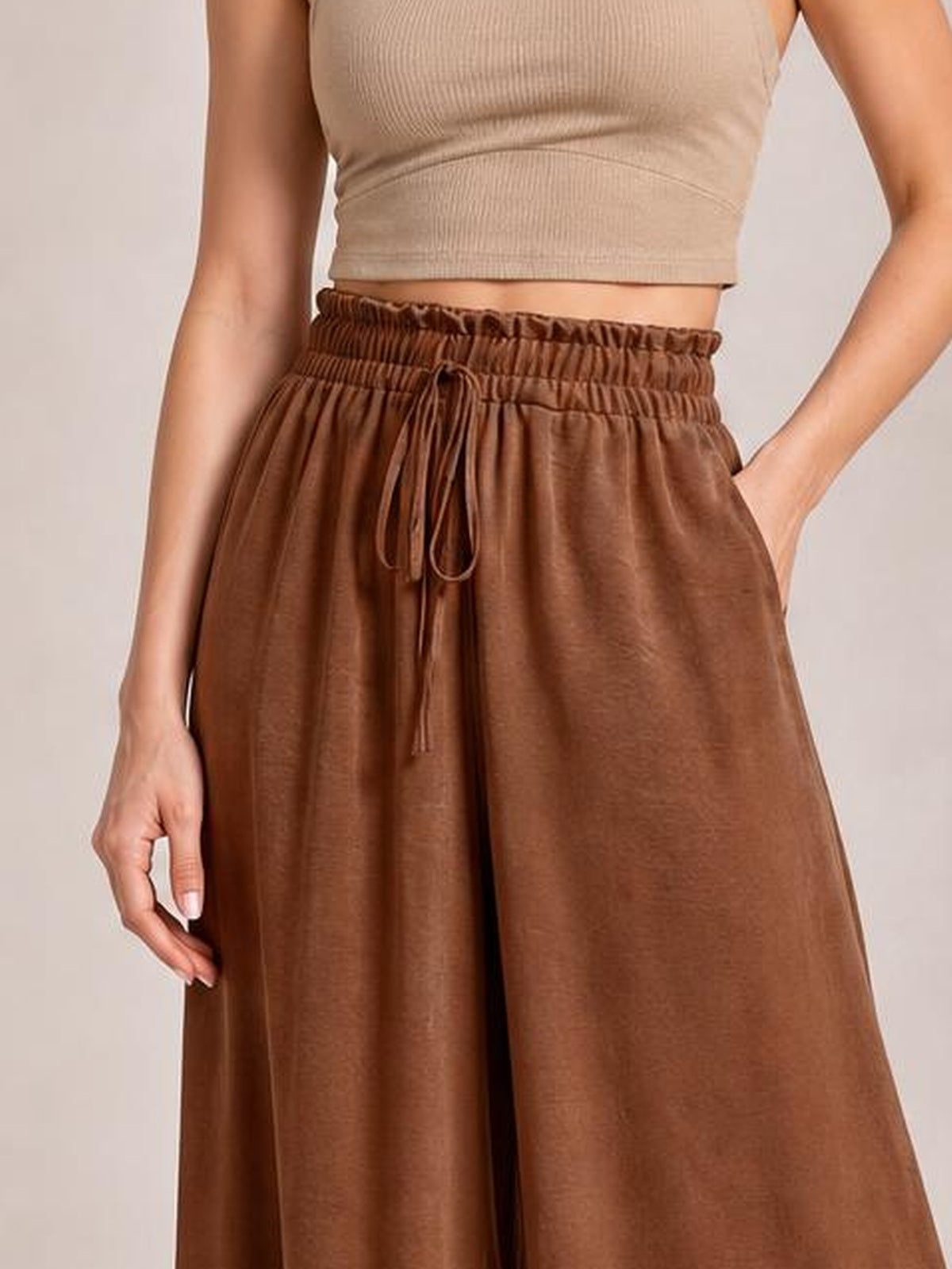 Model wearing brown tied high-waist wide-leg pants with an elastic waistband, drawstring closure, and flowing oversized silhouette.