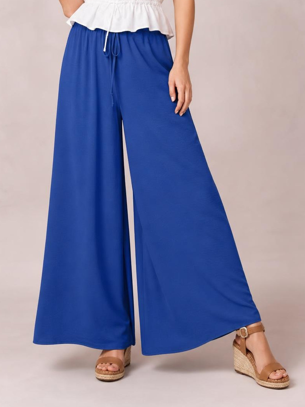 Model wearing royal blue high-waisted wide-leg pants with a drawstring tie, flowing opaque silhouette, and relaxed fit.