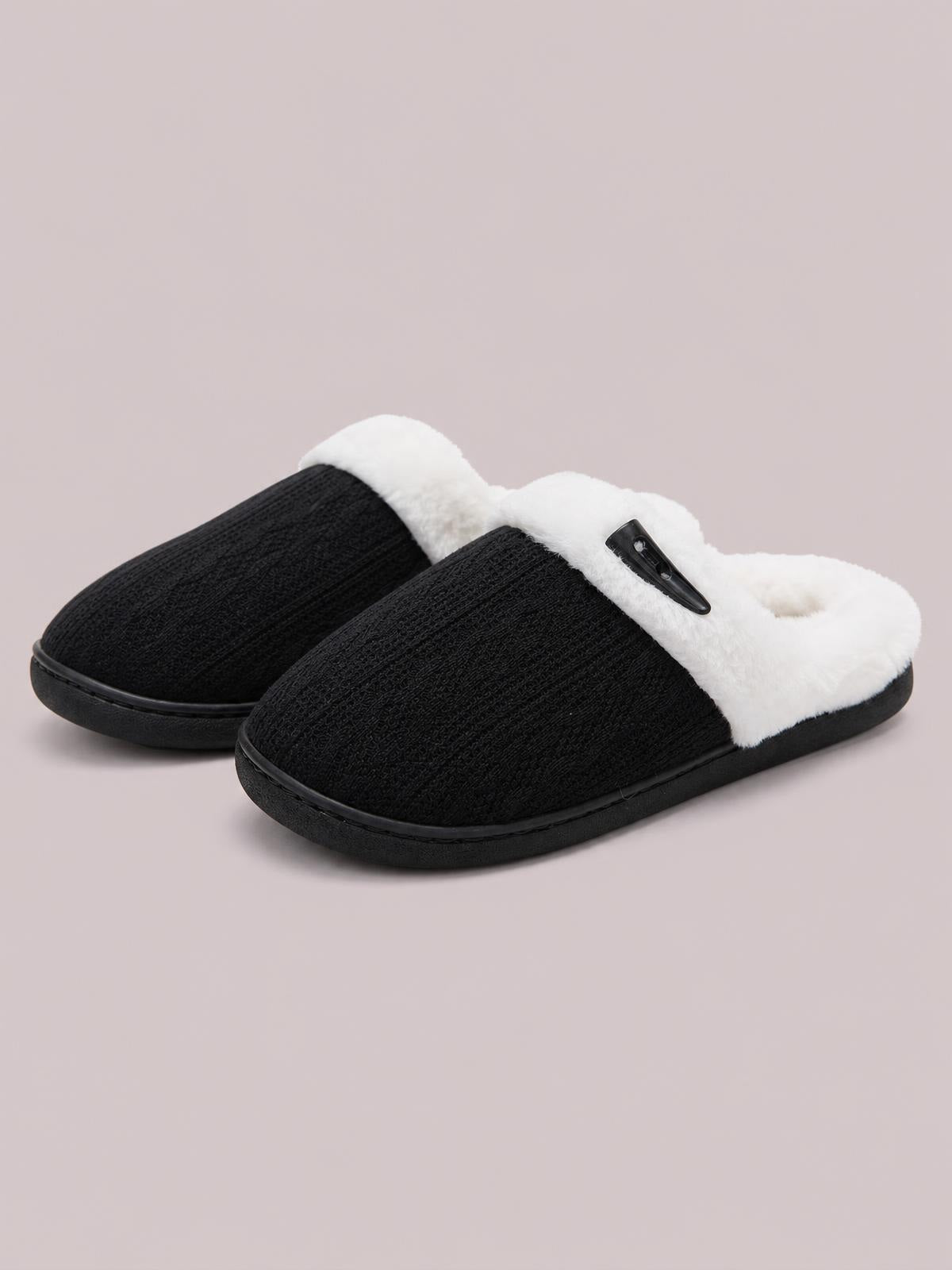 Black flat slippers feature textured fabric uppers, plush white furry lining, open backs, sturdy rubber soles, and a decorative horn-style buckle.