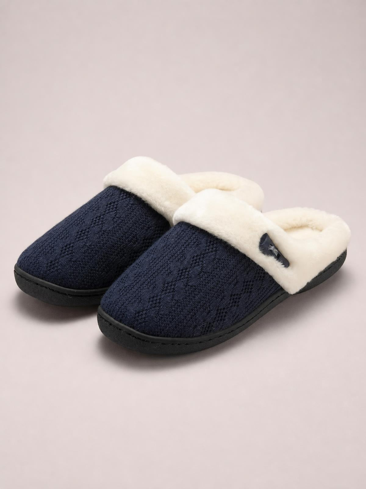 Pair of navy blue flat slippers with textured fabric uppers, plush cream furry trim, decorative buckle detail, and sturdy black rubber soles.