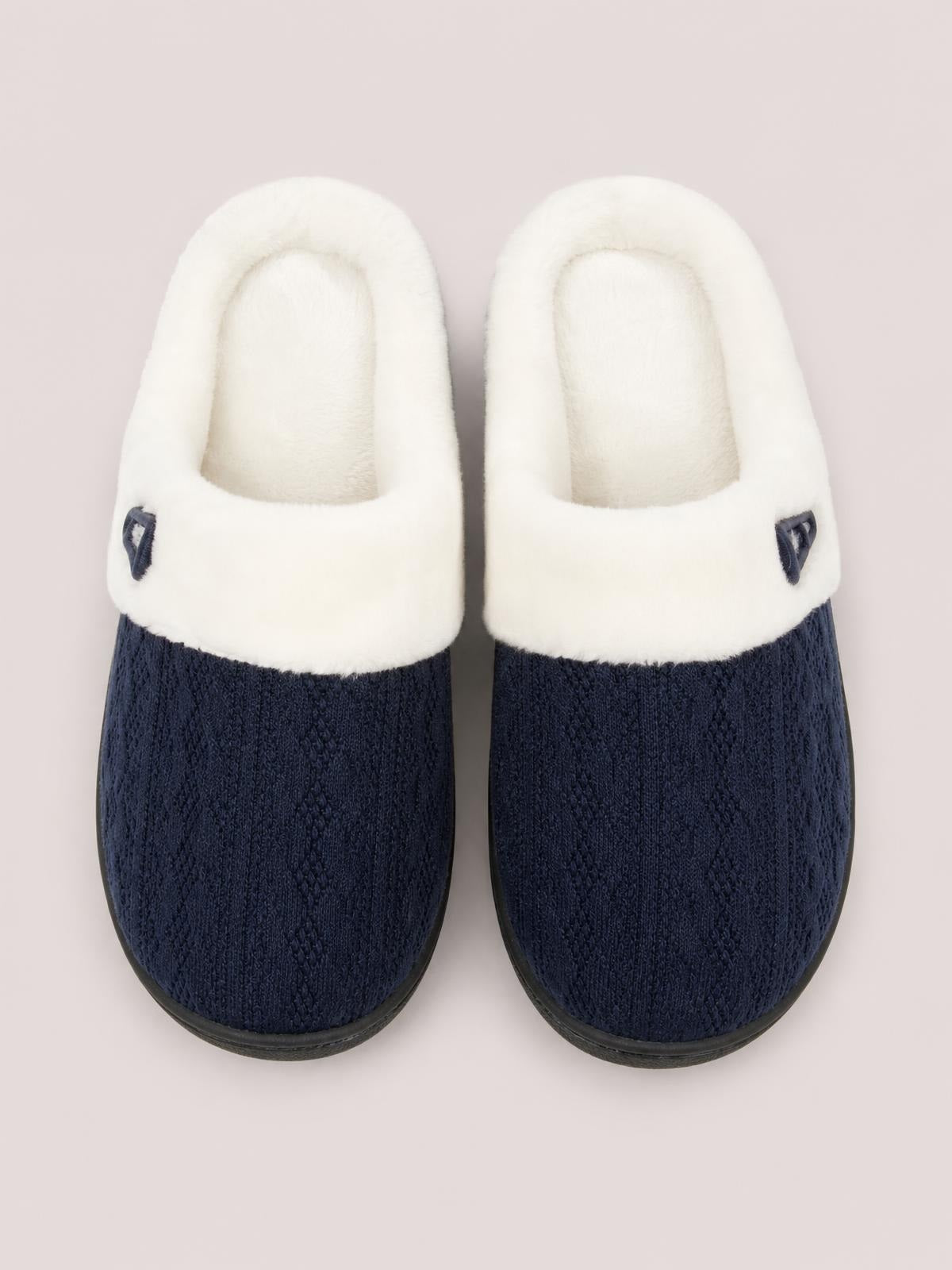 Navy blue furry-texture flat slippers with plush white lining, rounded toes, black rubber soles, and small horn-shaped buckle accents.