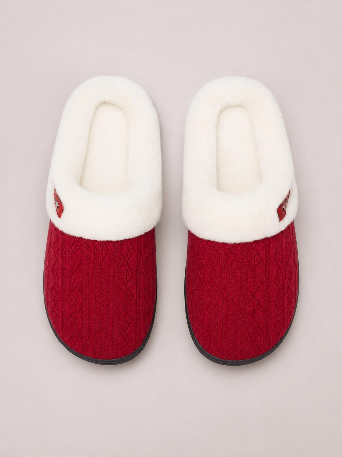 Pair of red flat slippers with textured fabric uppers, plush white furry lining, rounded toes, rubber soles, and small horn-style buckle accents.
