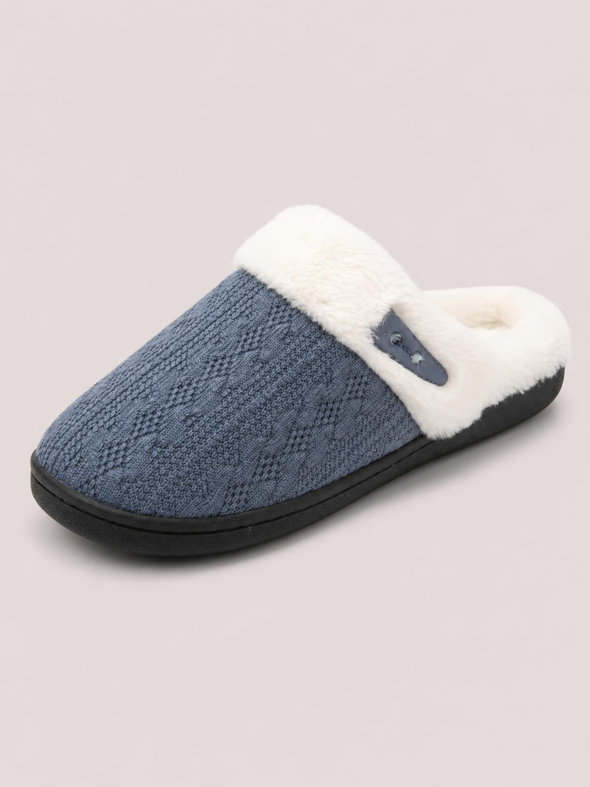 Blue-gray flat slipper with a textured knit upper, plush white furry lining, horn-style buckle detail, and a sturdy black rubber sole.