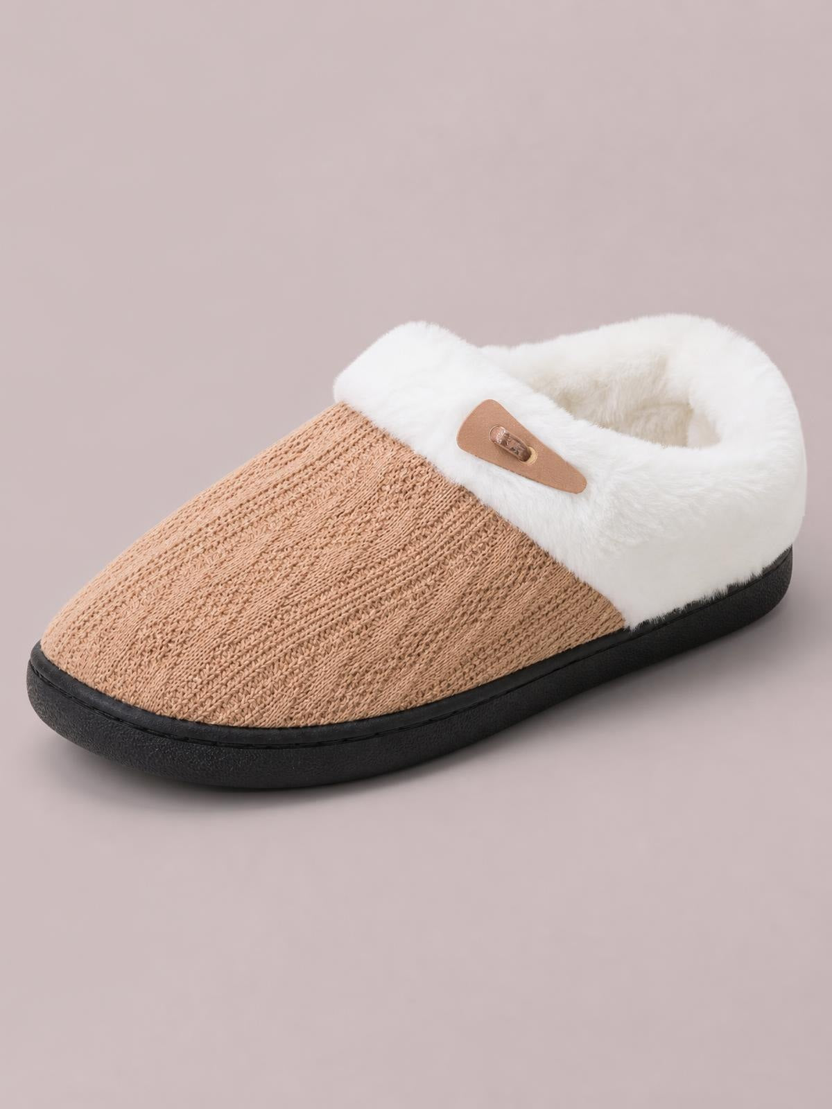 Tan furry-texture flat slipper with a knit-textured upper, plush white lining, horn-style buckle detail, rounded toe, and sturdy black rubber sole.