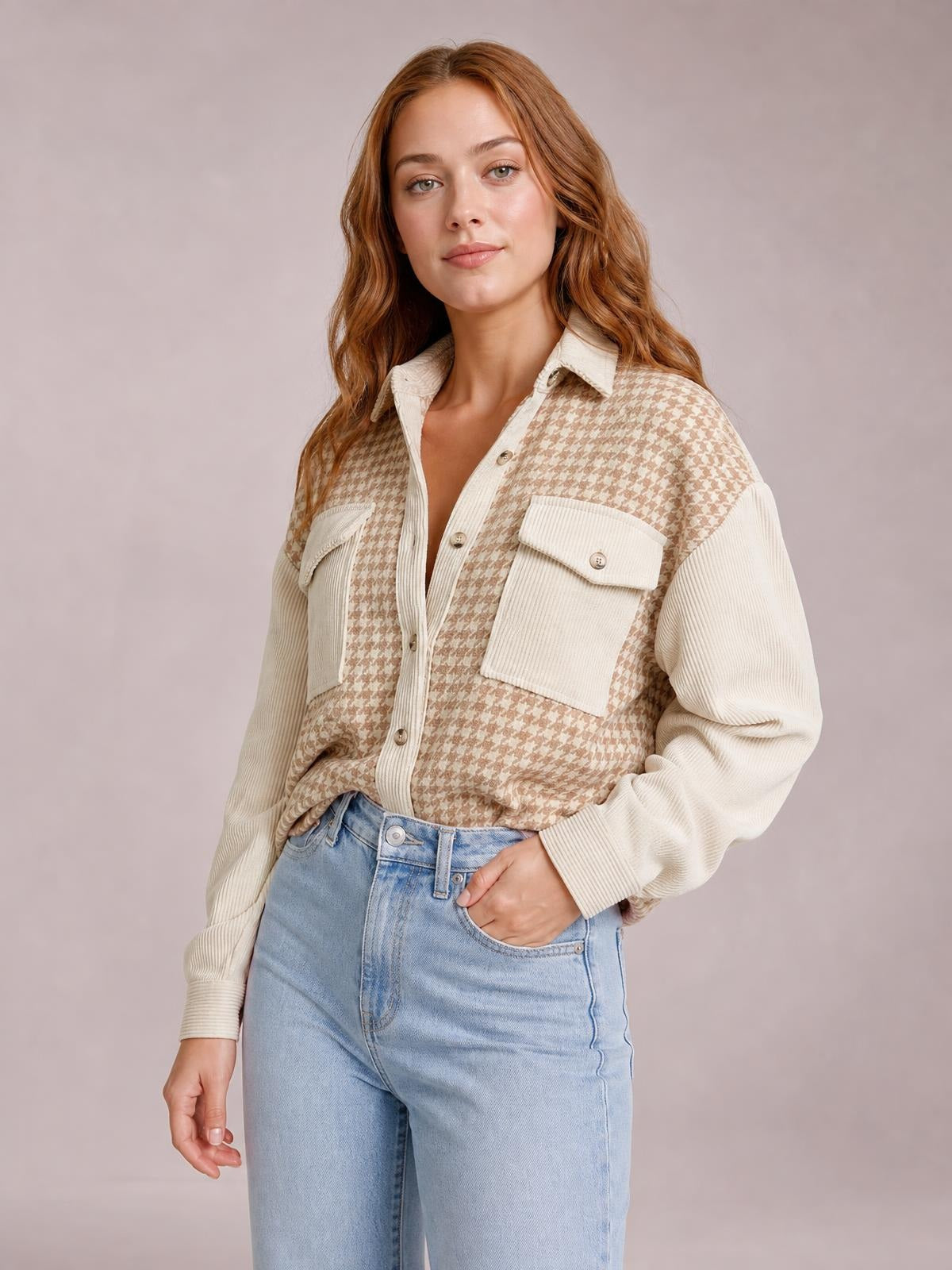 A woman models a cream and tan houndstooth button-down jacket with a collared front, relaxed silhouette, long sleeves, and two flap pockets.