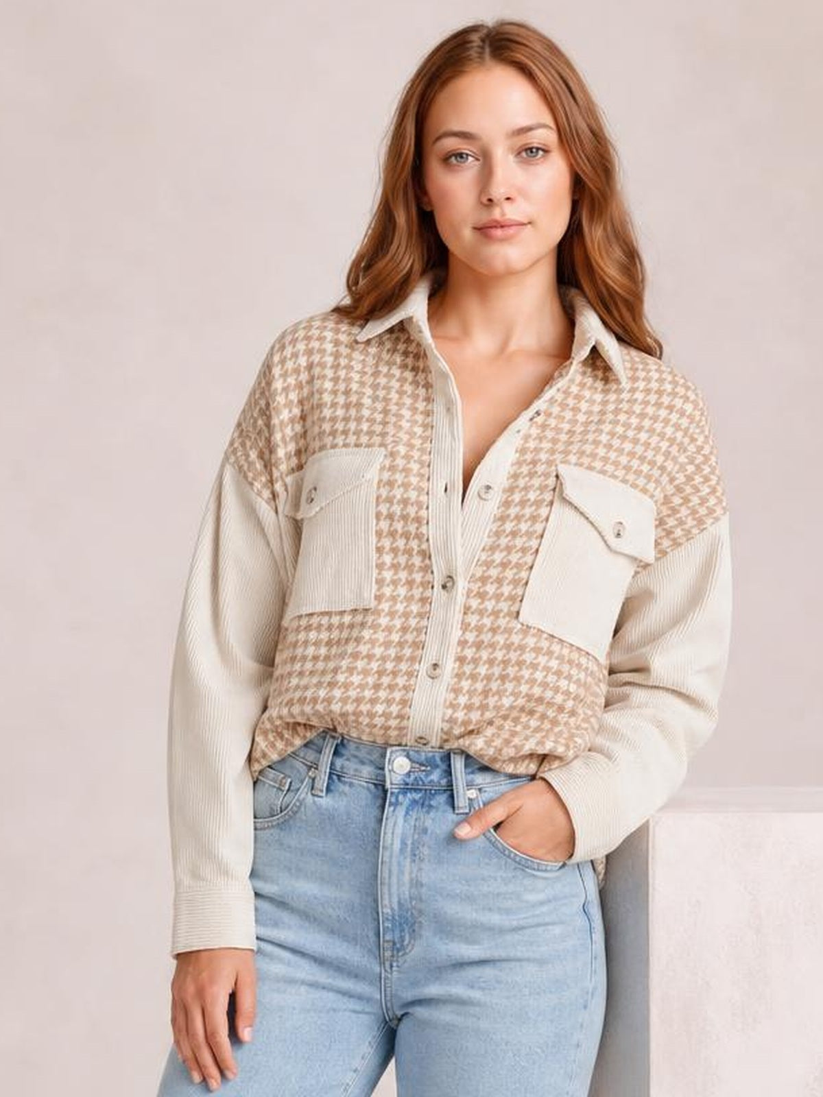Model wears a relaxed houndstooth button-down jacket in beige and cream with contrasting sleeves, a collared neckline, buttons, and flap pockets.