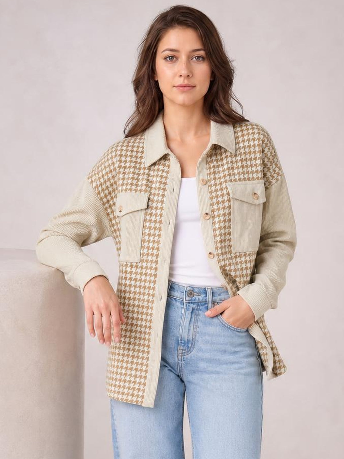Model poses in a relaxed beige and cream houndstooth button-up jacket with long sleeves, a collar, front buttons, patch pockets, and a straight silhouette.