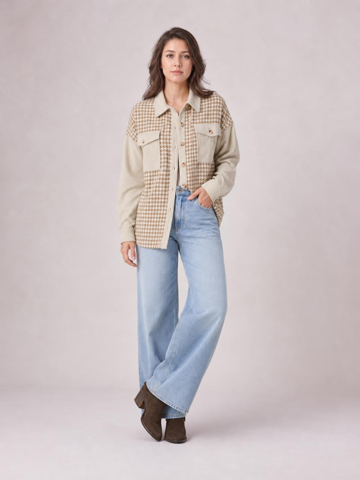 A model stands with one hand in her pocket wearing a beige houndstooth button-up jacket with long sleeves, a relaxed silhouette, collar, and patch pockets.