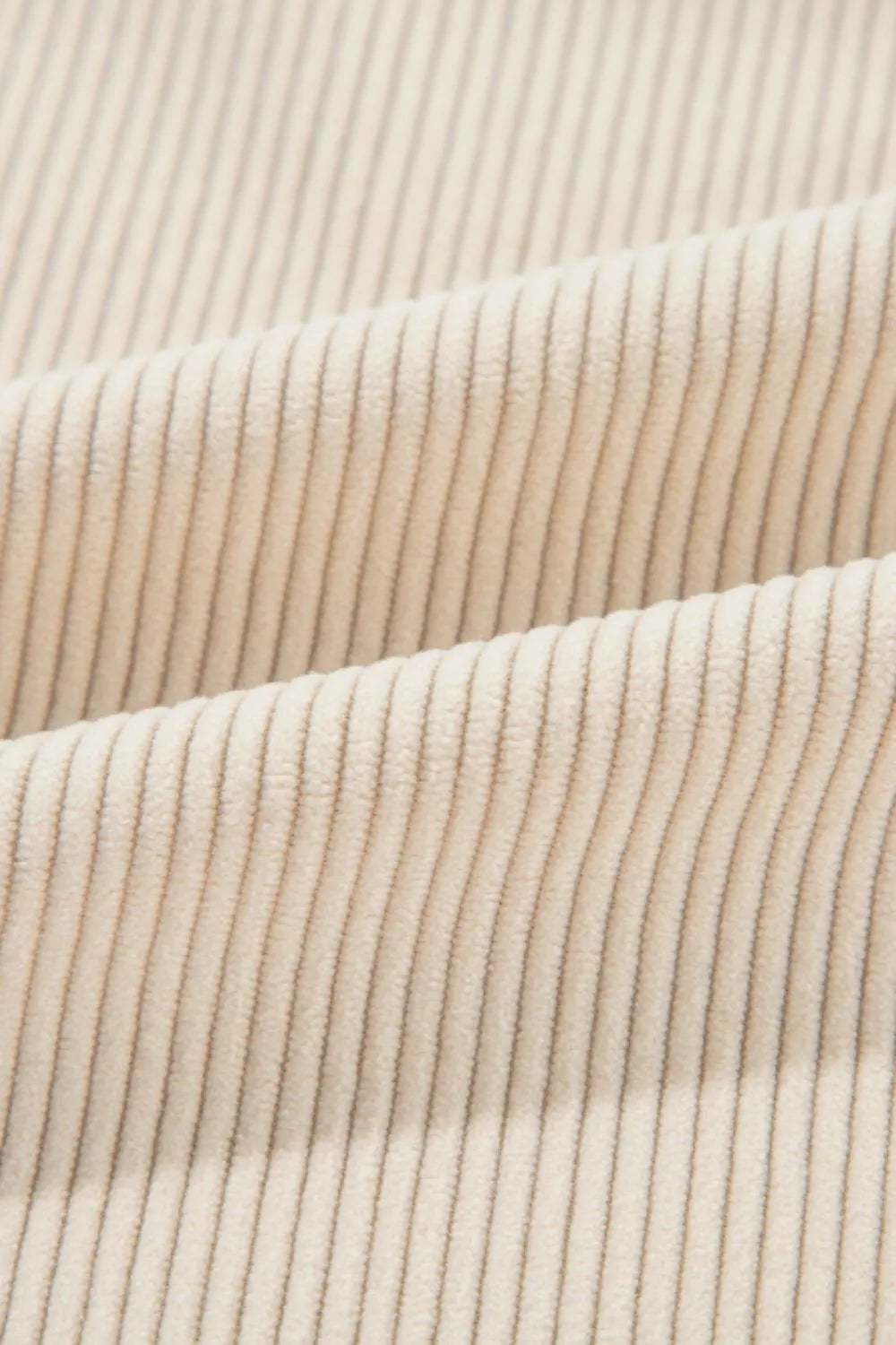 Close-up of the jacket’s cream-colored fabric, showing a soft vertical ribbed texture and folded construction detail.