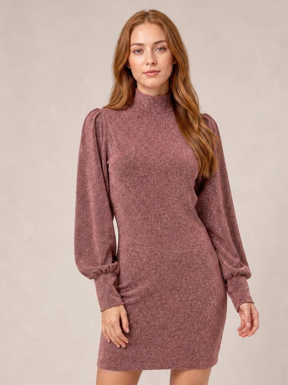 A model poses in a mauve glitter mock neck mini dress with a figure-hugging silhouette, long gathered bishop sleeves, and fitted construction.