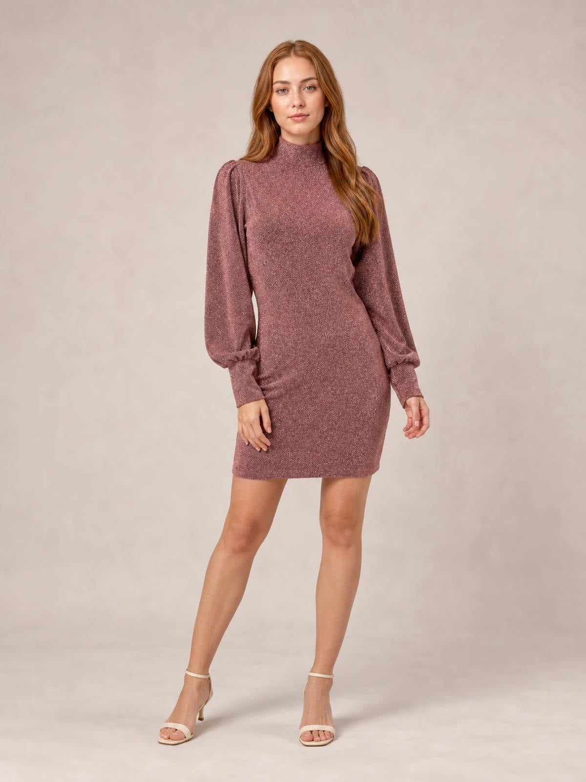 A model poses in a mauve glitter mock neck mini dress with long bishop sleeves, a fitted silhouette, and a straight hem above the knee.