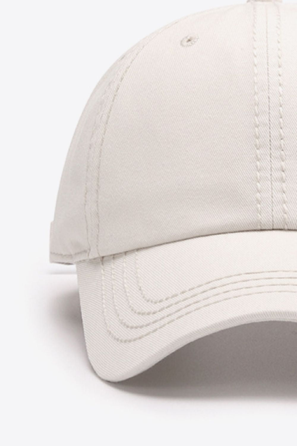 A solid ivory cotton baseball cap features a softly structured crown, curved brim, and neatly defined tonal stitching for a polished everyday silhouette.