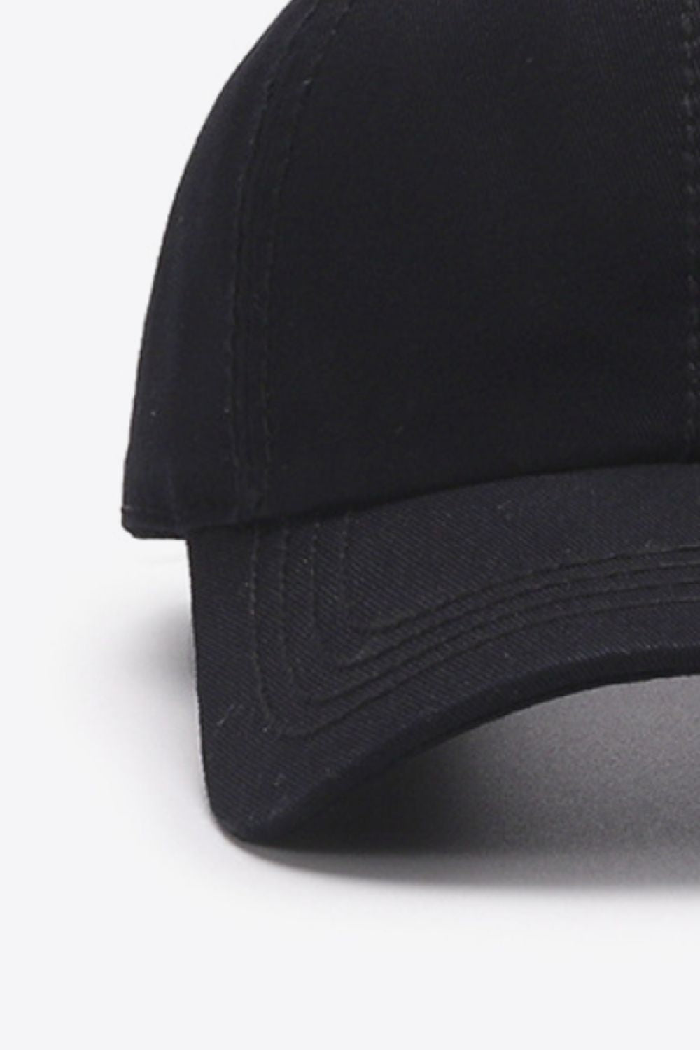 A close-up flat lay shows the black In A Pretty World cotton baseball cap with a softly structured crown, curved brim, and neat tonal stitching.