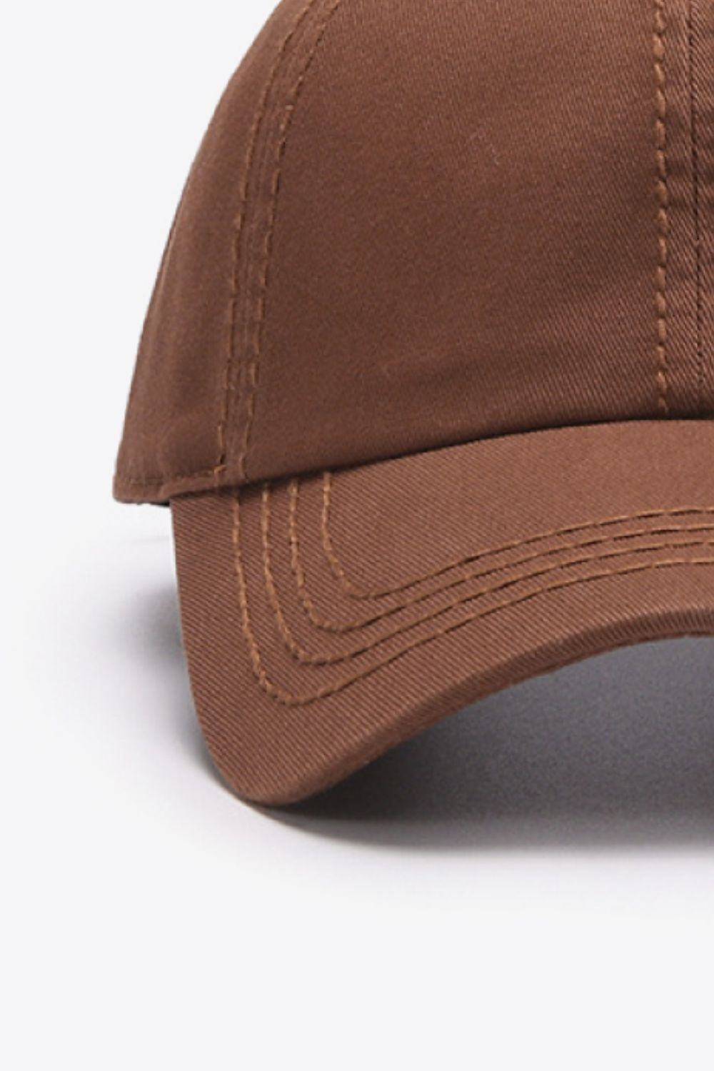 Close-up flat lay of a solid brown cotton baseball cap with a softly structured crown, curved brim, and neatly defined tonal stitching.