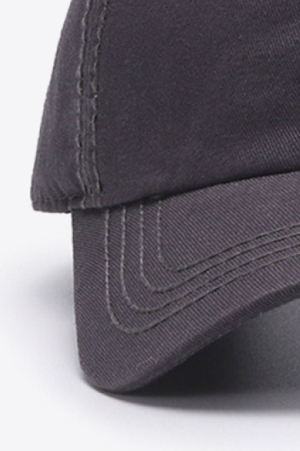 Close-up of the dark solid In A Pretty World baseball cap showing its softly structured crown, curved brim, and neatly defined tonal stitching.