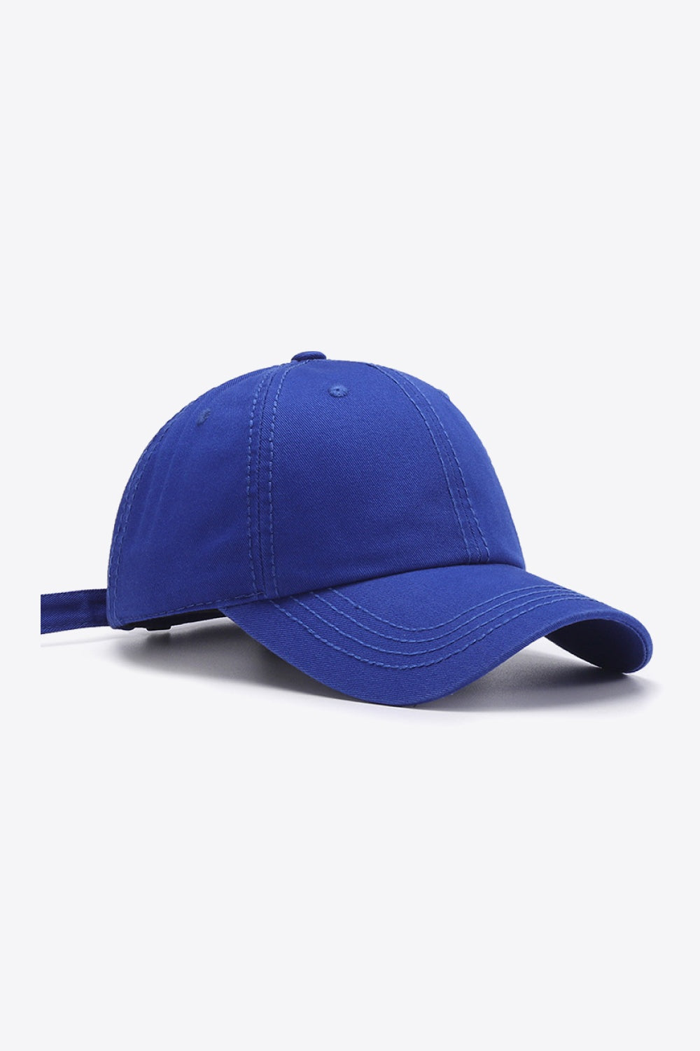 A solid blue cotton baseball cap features a softly structured crown, curved brim, defined panel stitching, and an adjustable rear strap.