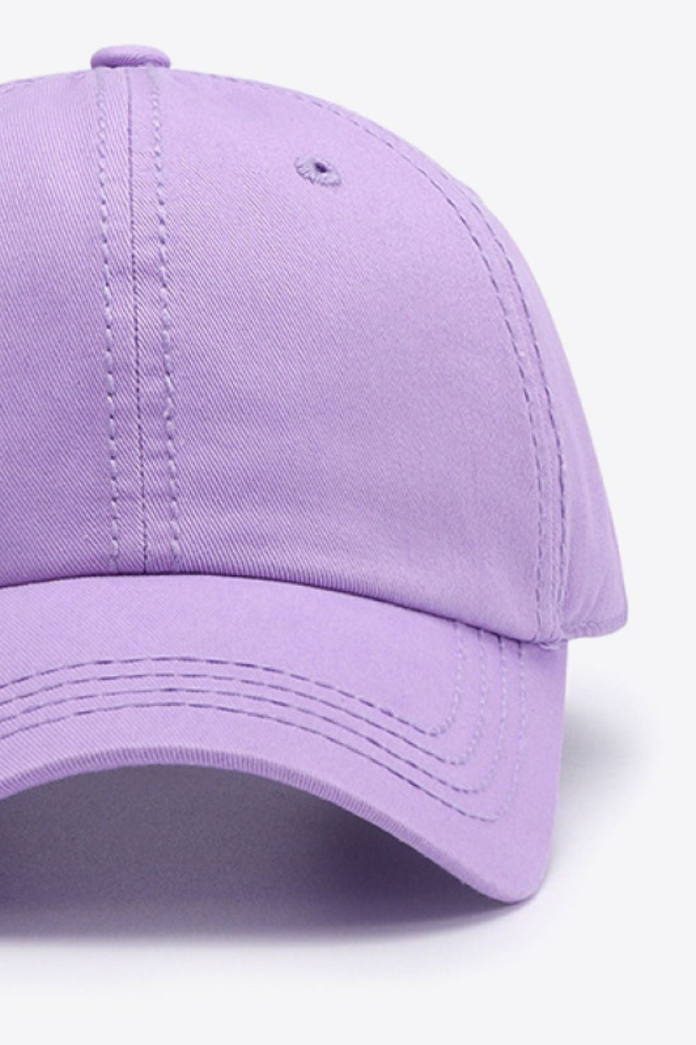 Lavender cotton baseball cap with a softly structured crown, curved brim, top button, ventilation eyelet, and neatly defined tonal stitching.