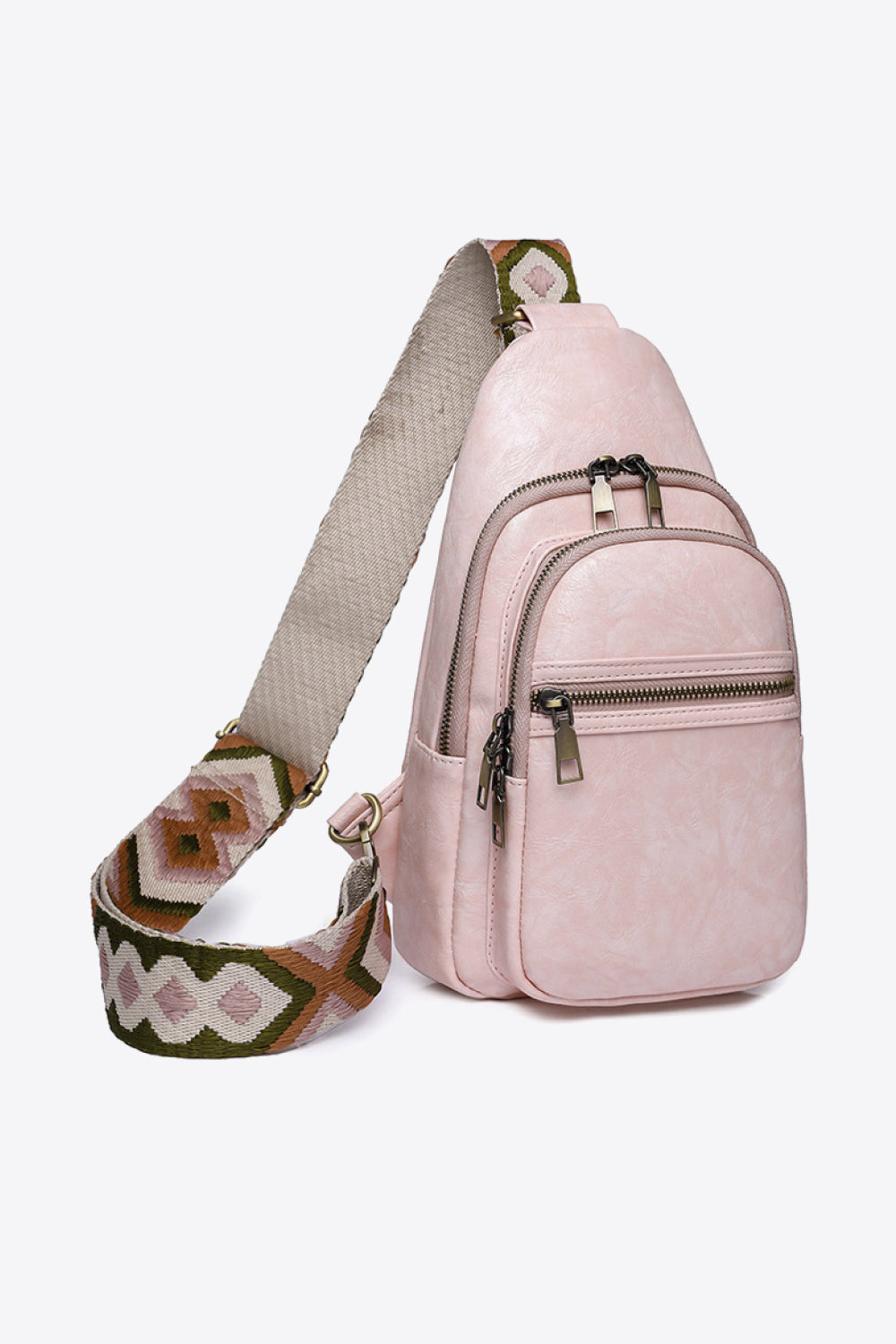 Pale pink PU leather sling bag with a compact vertical silhouette, multiple zip compartments, metal pulls, and a wide patterned adjustable strap.