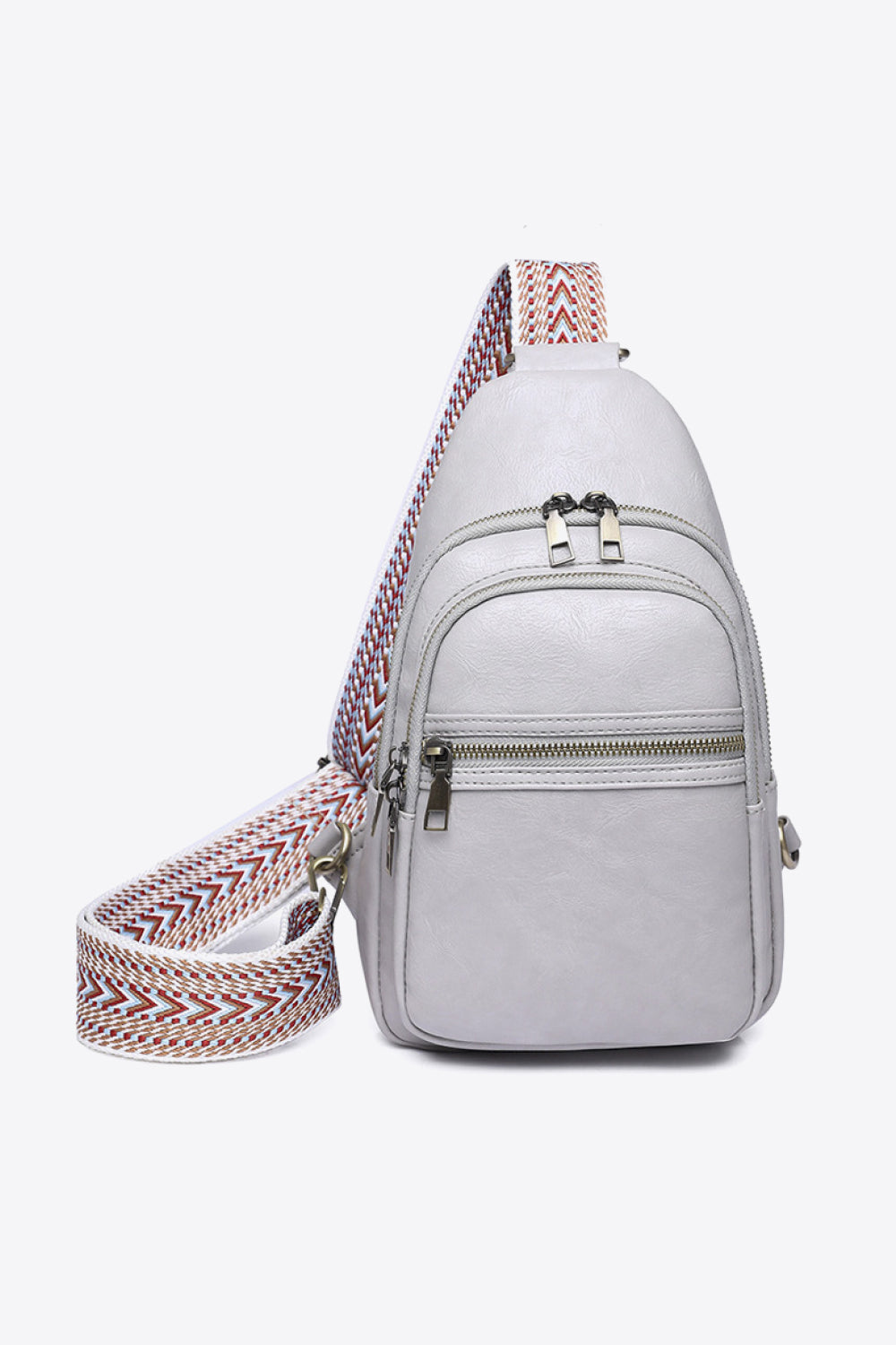 White PU leather sling bag with a compact vertical silhouette, multiple front zip compartments, metal pulls, and a wide patterned strap.
