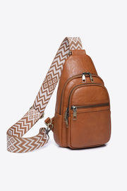 Brown PU leather sling bag with a compact vertical silhouette, patterned adjustable strap, layered zip compartments, and polished metal pulls.