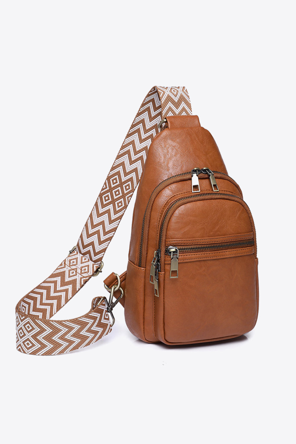 Brown PU leather sling bag with a compact vertical silhouette, patterned adjustable strap, layered zip compartments, and polished metal pulls.