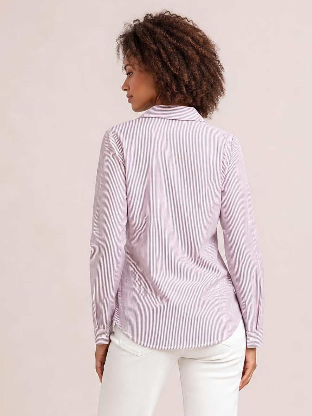 A model stands with her back to the camera in a pink-and-white striped blouse with a Johnny collar, long sleeves, button cuffs, and a relaxed regular silhouette.