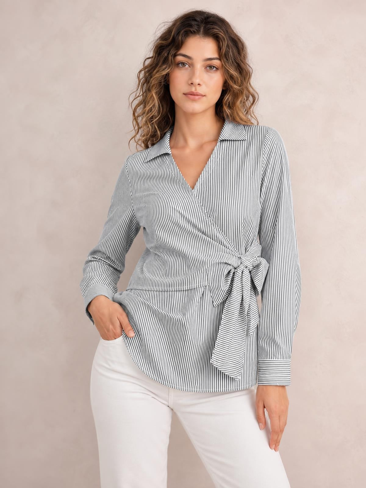 A model poses in a gray-and-white striped blouse with a Johnny collar, V neckline, long sleeves, and a bow tie waist creating a wrapped silhouette.