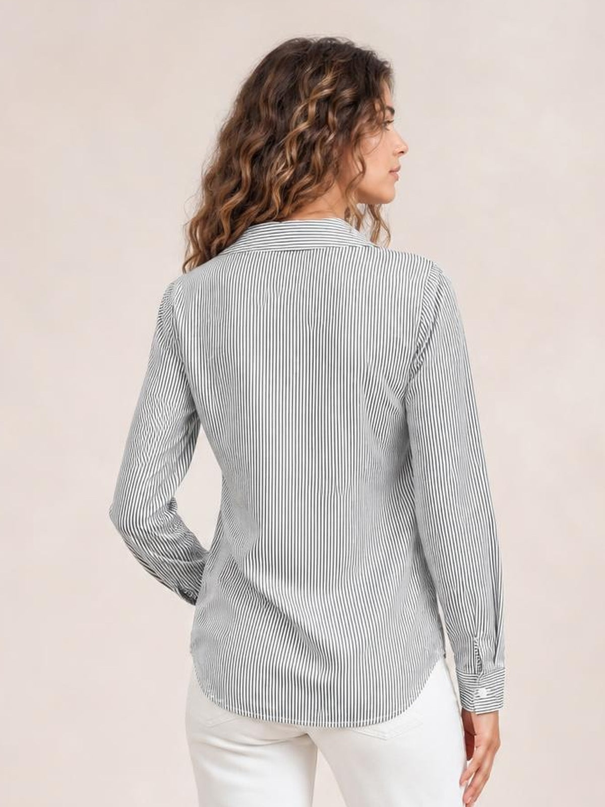 Model shown from behind in a gray-and-white striped blouse with a Johnny collar, long sleeves, regular silhouette, curved hem, and one hand on her hip.