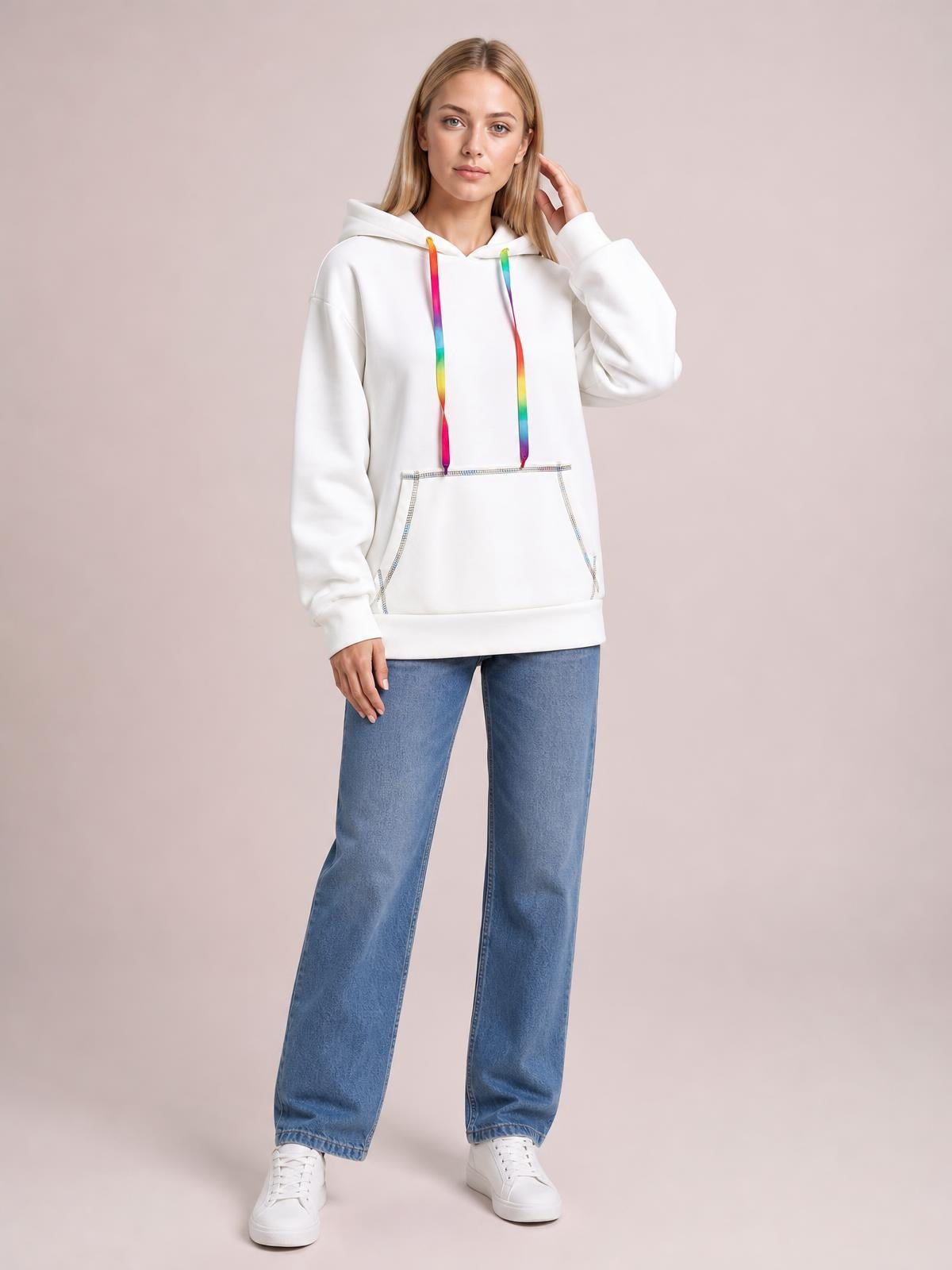 A model poses in a white drawstring hoodie with colorful cords, contrast stitching, raglan sleeves, a kangaroo pocket, and a relaxed silhouette.