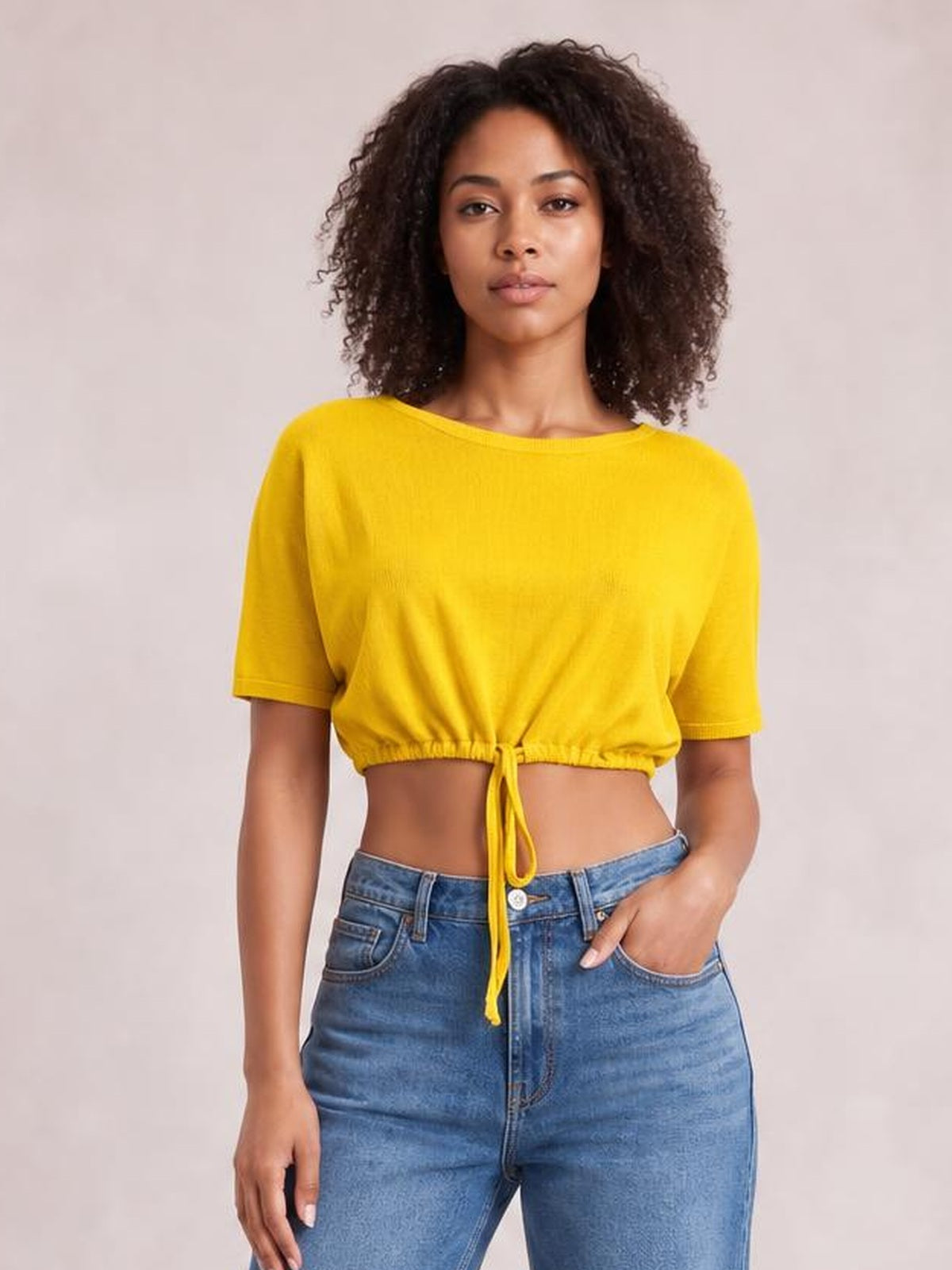 Model wears a bright yellow drawstring round neck short sleeve T-shirt with a cropped, relaxed silhouette and adjustable gathered hem.