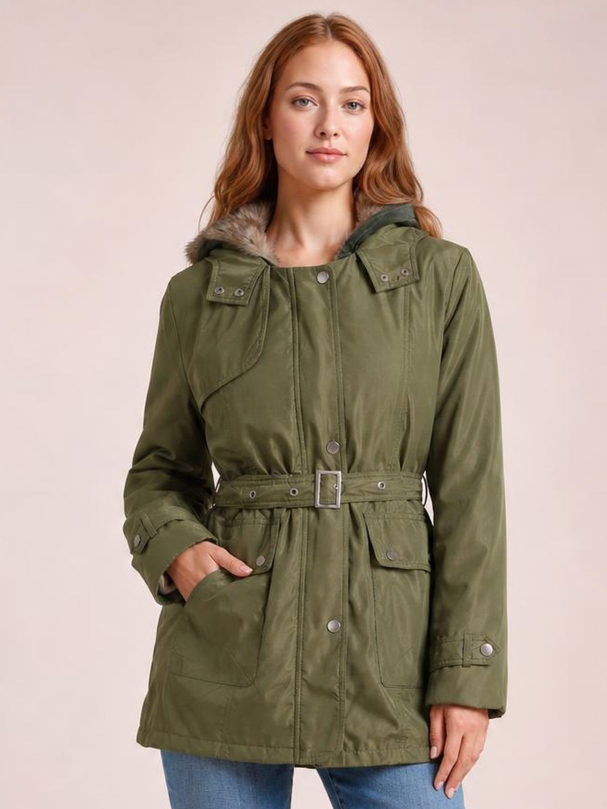 Model poses in an olive-green hooded jacket with a detachable faux-fur liner, button closure, belted waist, and multiple flap pockets.