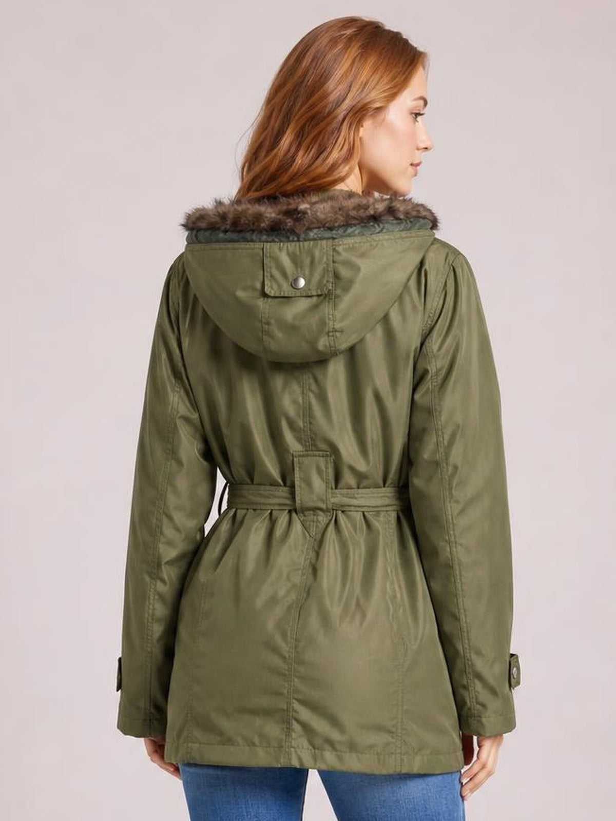 Model shown from the back in an olive-green hooded jacket with a detachable faux-fur-lined hood, buttoned pocket, long sleeves, and cinched waist belt.