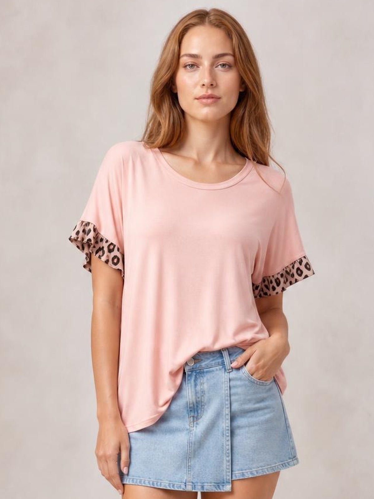 A model poses in a relaxed pink round-neck short-sleeve T-shirt with leopard-print sleeve trim and a loose, flowing silhouette.