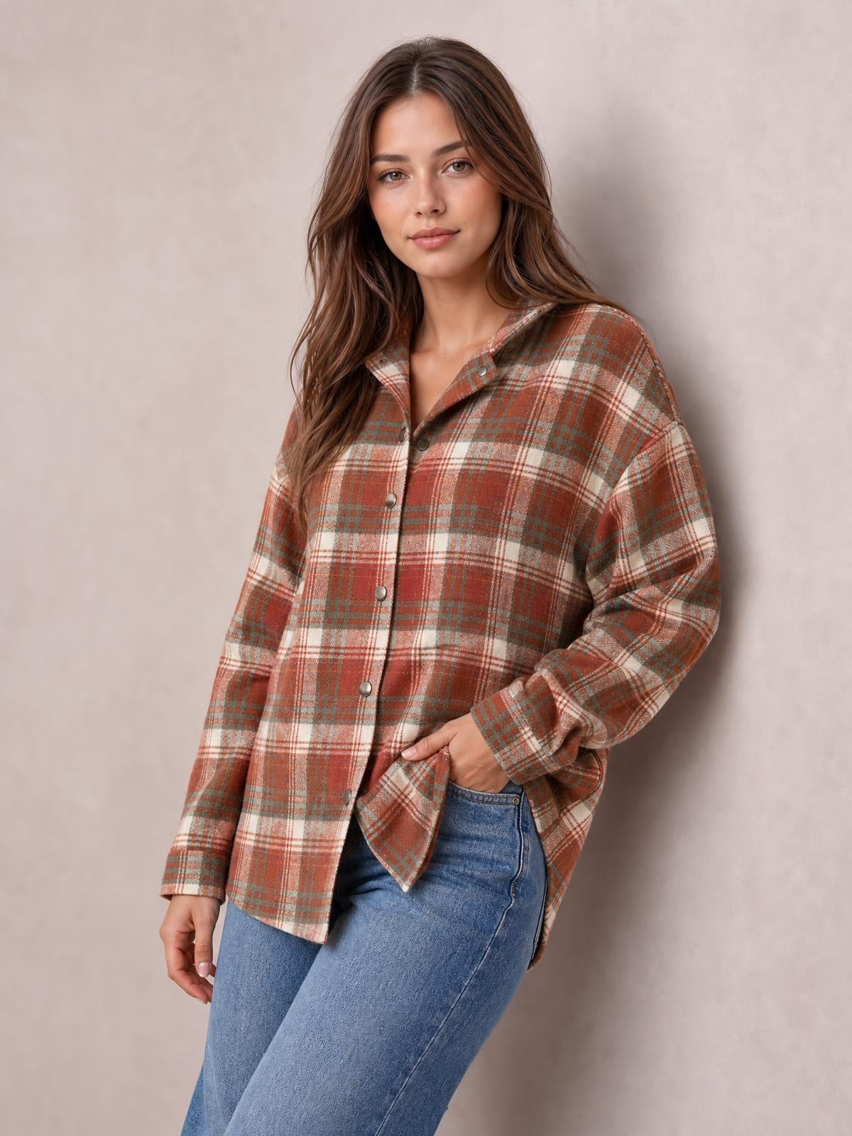 A model wears a relaxed rust, cream, and gray plaid hooded jacket with long sleeves, button front, roomy silhouette, and hands tucked into its pockets.