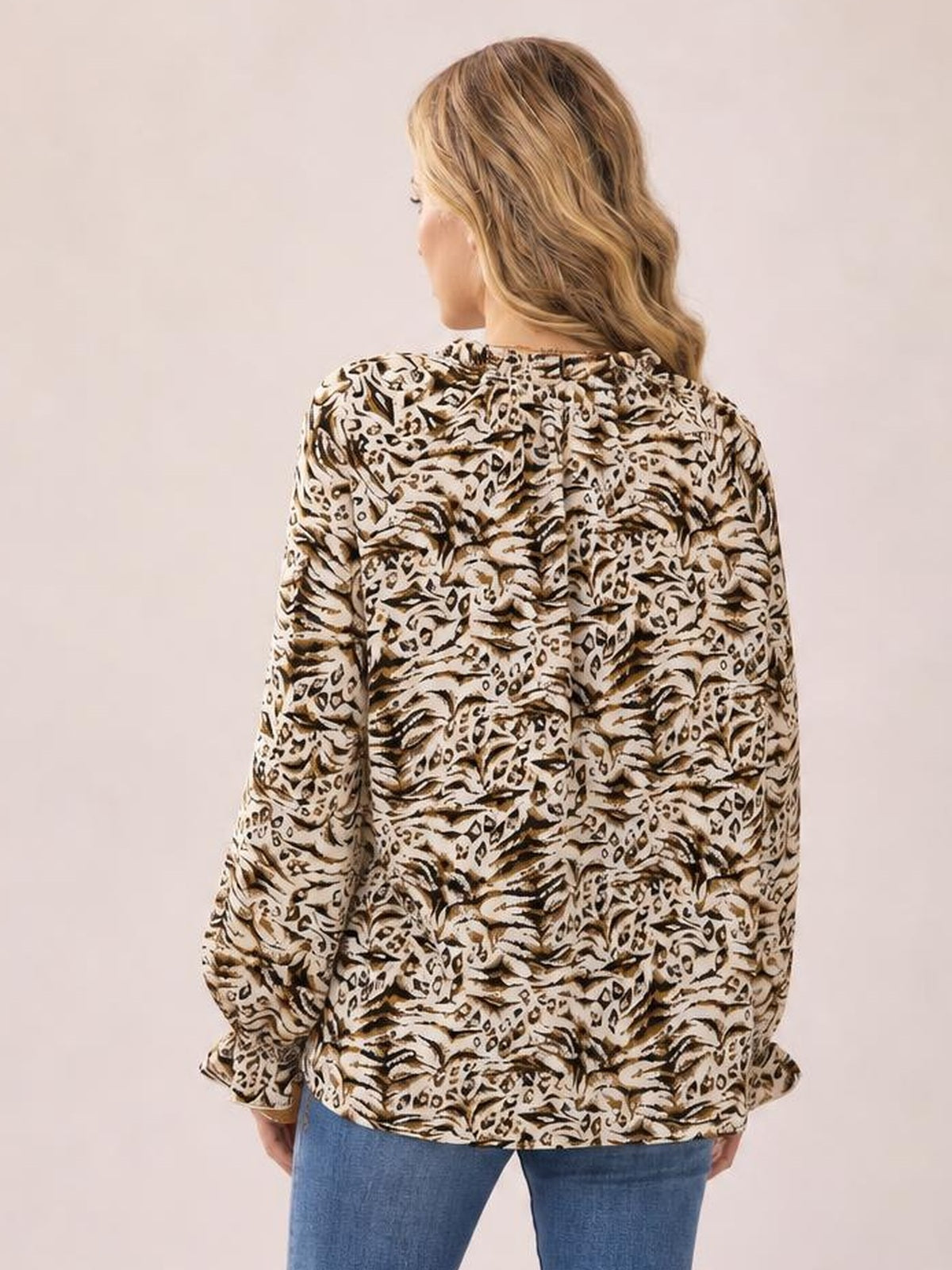 Back view of a model in a beige-and-brown printed blouse with a gathered frill-trim neckline, long sleeves, flared cuffs, and a relaxed long silhouette.