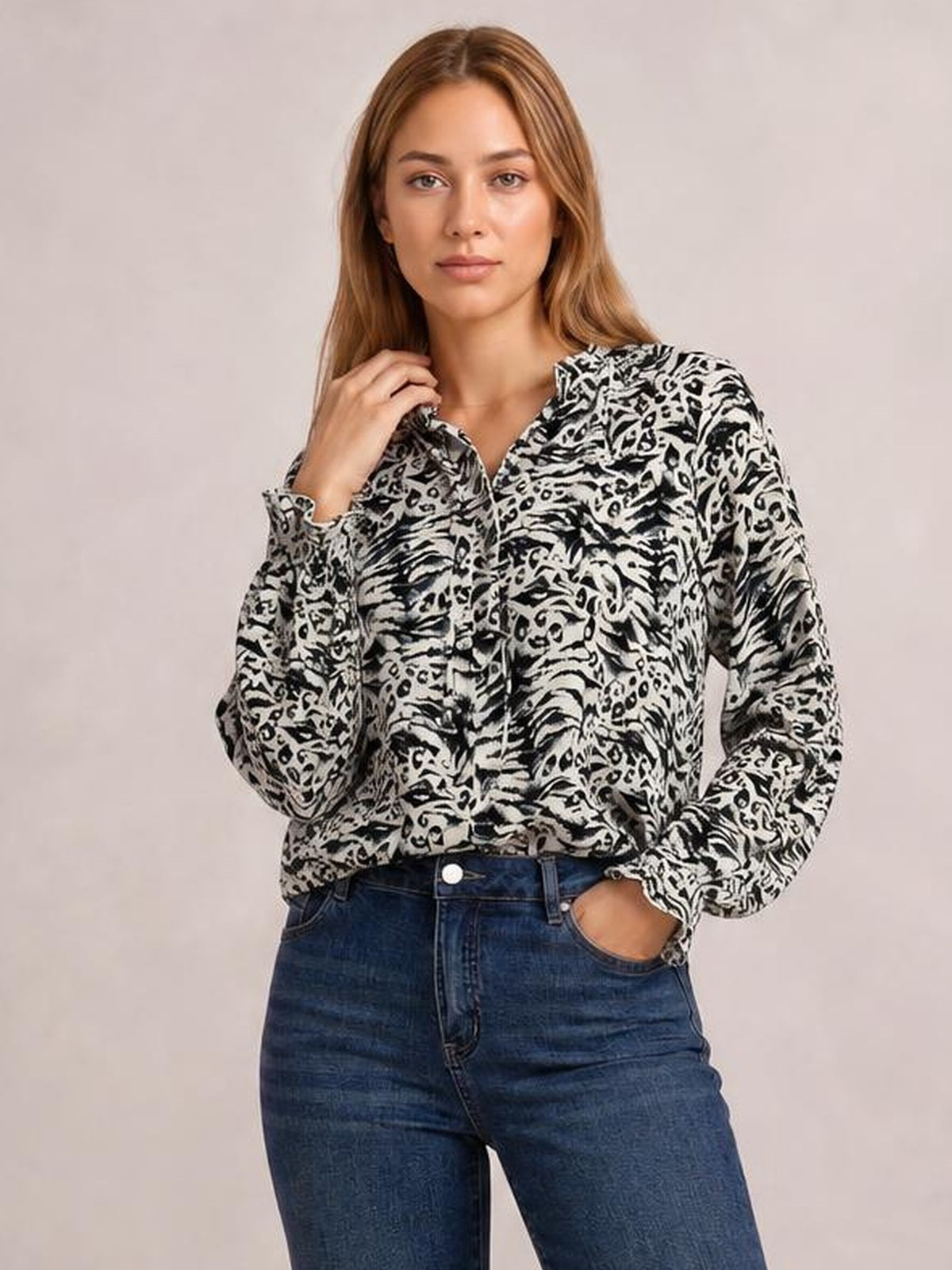 A model poses in a black-and-white printed blouse with a frill-trim tie neckline, long flounce sleeves, button front, and relaxed silhouette.